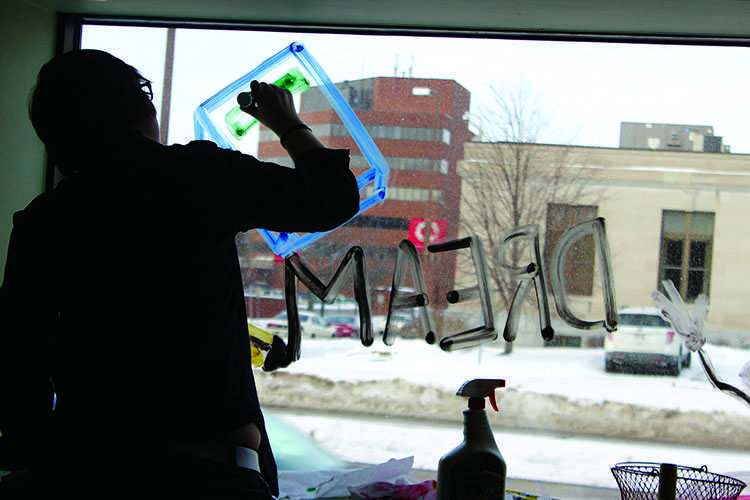 UW-Eau Claire student Ali Konz paints a window at the Eau Claire Boys and Girls Club Monday afternoon as part of the Martin Luther King Jr. Day service project. © 2014 Nick Erickson