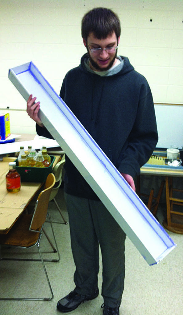 Michael Yohn, junior physics education major, holds the halfpipe built to study liquid flows. © 2014 Glen Olson