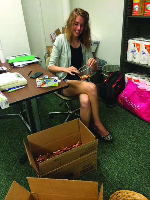 Aubry Reed, a senior, adds candy bars to the selection of food at Campus Harvest, the new food pantry at UW-Eau Claire.
