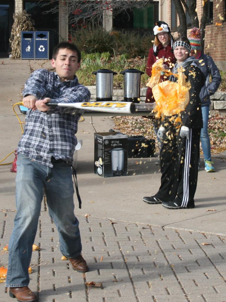 Fellow students watch as freshman chemistry major Chris Hartwick takes his turn at pumpkin smashing. - Photo by Austin Mai
