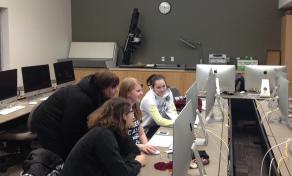 Students gather around a Mac computer in the CJ departments Mac lab earlier this week.