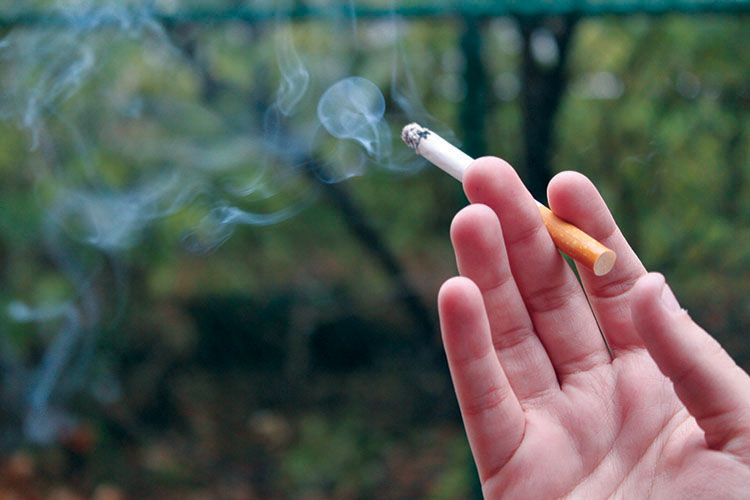 A UWEC student stops to smoke in a designated area and poses before heading to their next class. 