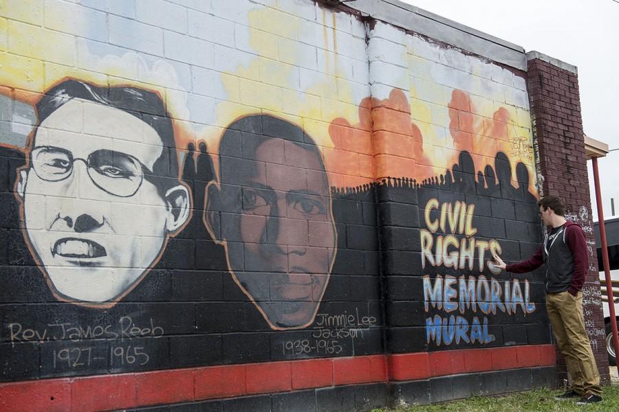 A student poses with a mural found on the Civil Rights Pilgrimage.
