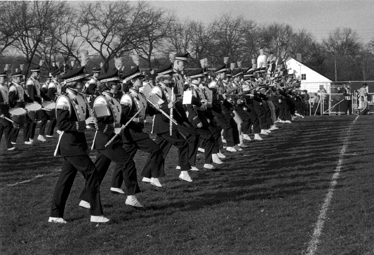 The College Band, now known as the Blugold Marching Band, performed only as a marching band in fall. When winter came, they converted to a concert band. Here, students perform on a field in fall 1965.