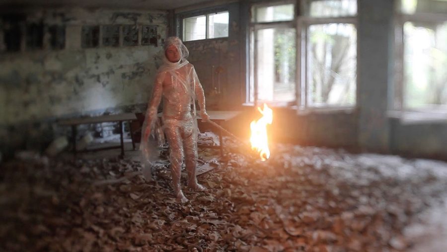 A still from the film shows Fedor Alexandrovich standing in an abandoned classroom littered with gas masks.