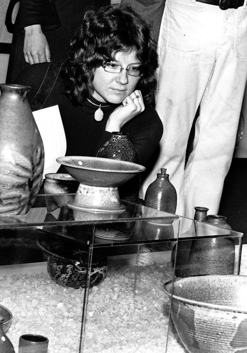 A 1973 photo of a student looking at pottery.