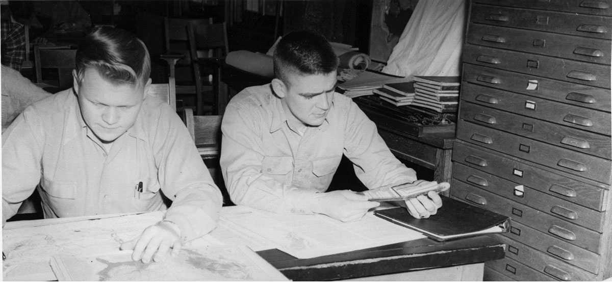 Physical geography involves landforms and environmental patterns. Shown here are students looking at maps in a geography lab class in the 1950s.