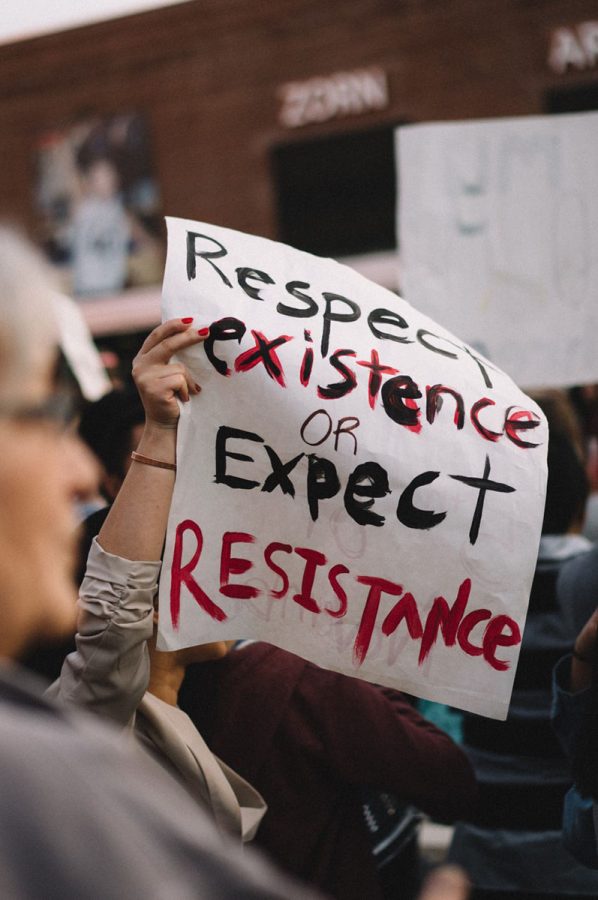 A student holds a sign as Donald Trump visits campus.