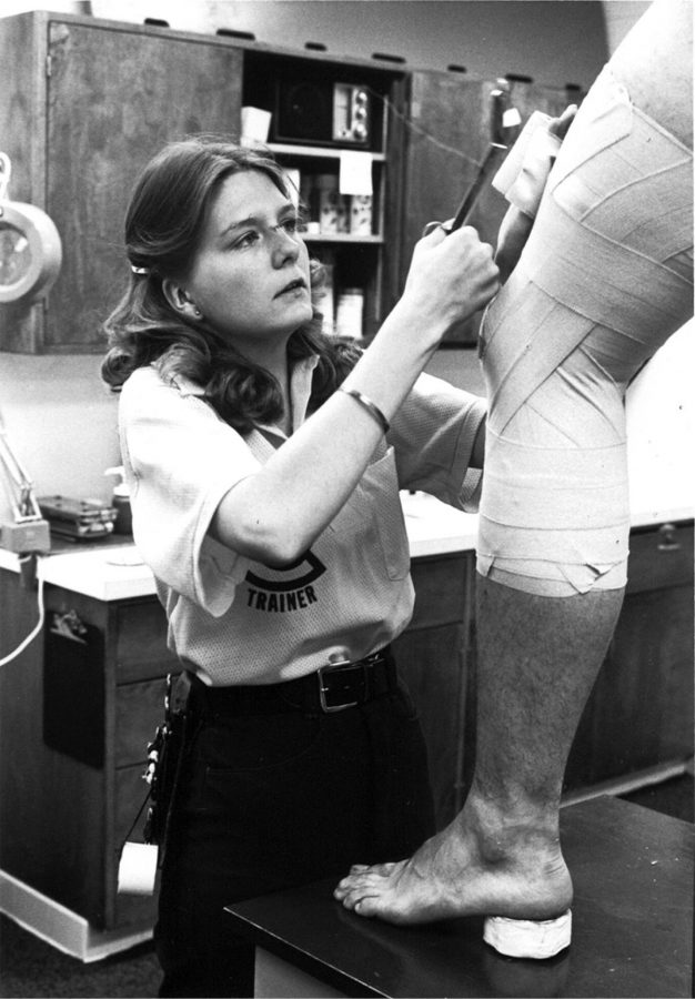 Pictured is athletic trainer, Barb Jenneman taping a football player’s leg in 1979. Barb was trainer for the mens football team, an example of a possible career for a Kinesiology student. 