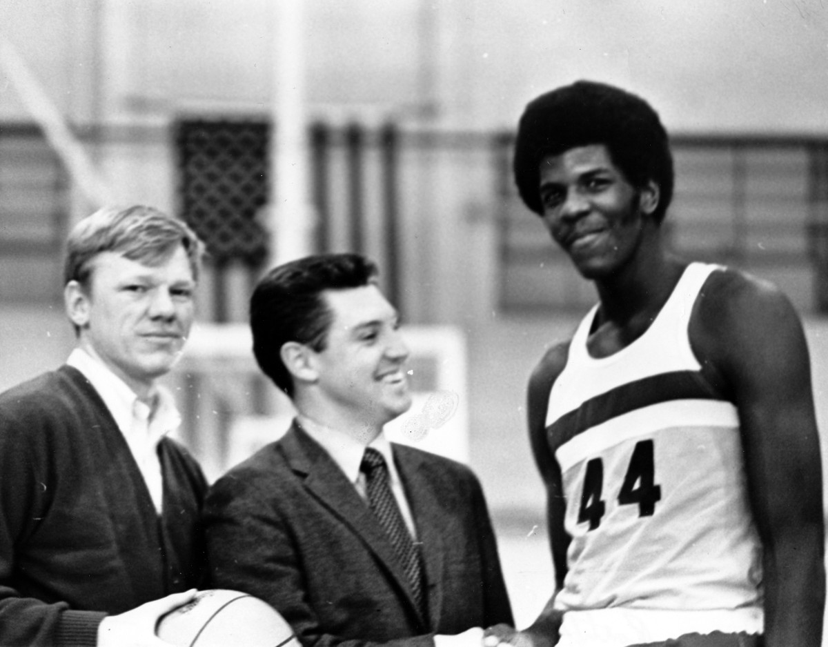 This picture displays Mike Ratliff, a UW-Eau Claire basketball player shaking hands with Jim Bollinger, assistant chancellor for facilities planning and management during 1971. 
