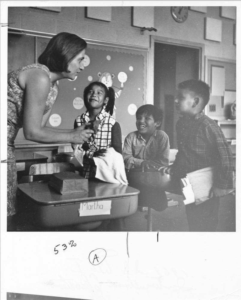 This 1969 photograph shows a teacher talking to three students at a Campus School Summer Project.