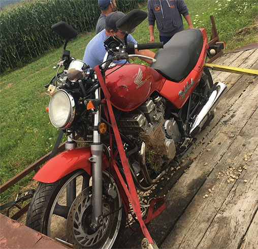 Totalled motorcycle being loaded onto a trailer after being forced off the road by a distracted driver.