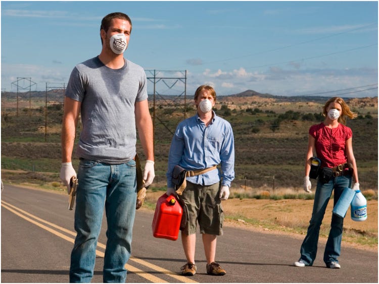 Three people with face masks stand in a road.