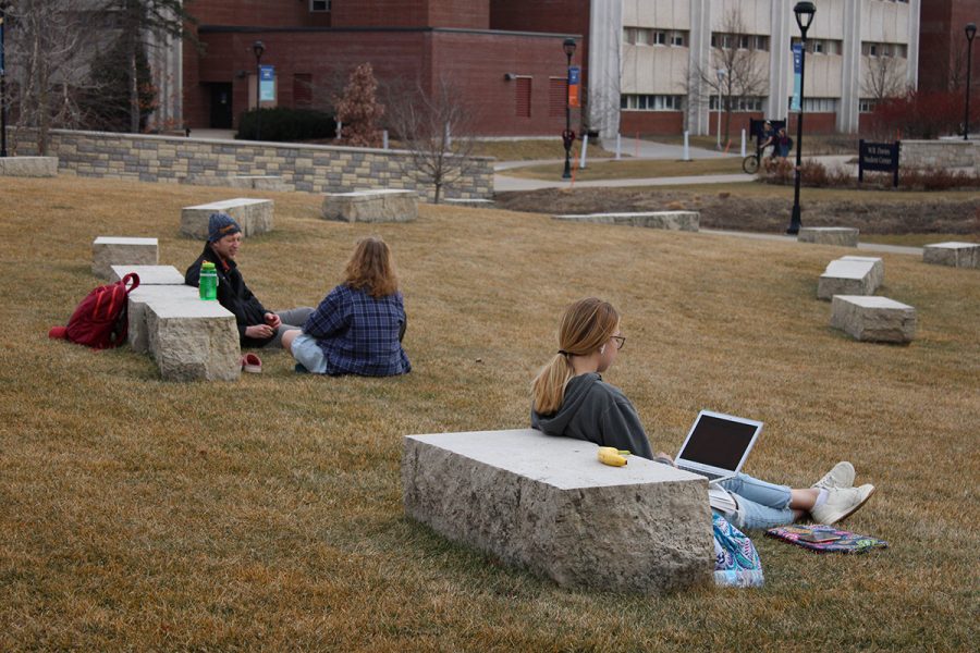 Students sit near the rocks on the campus mall as the temperatures reach the 50s and 60s this week.