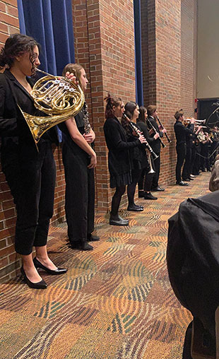 Students stand in aisle as they play Ave Verum Corpus.