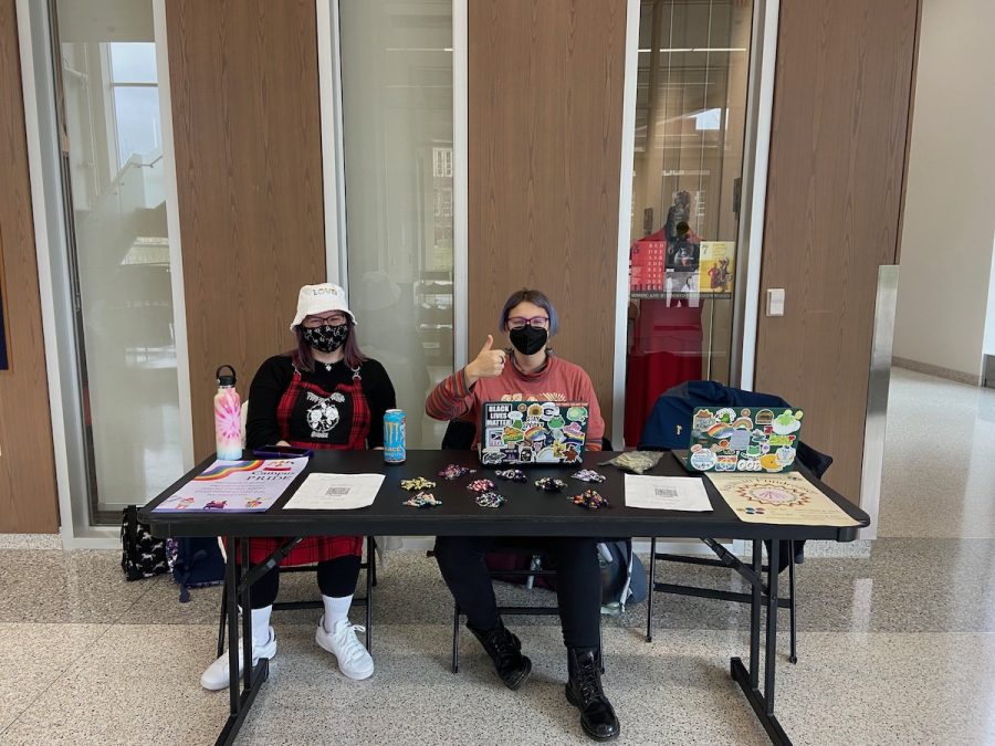 Stephanie Janssen (she/her) and Tyler Warwick-Mick (they/them) sell keychains in Centennial.