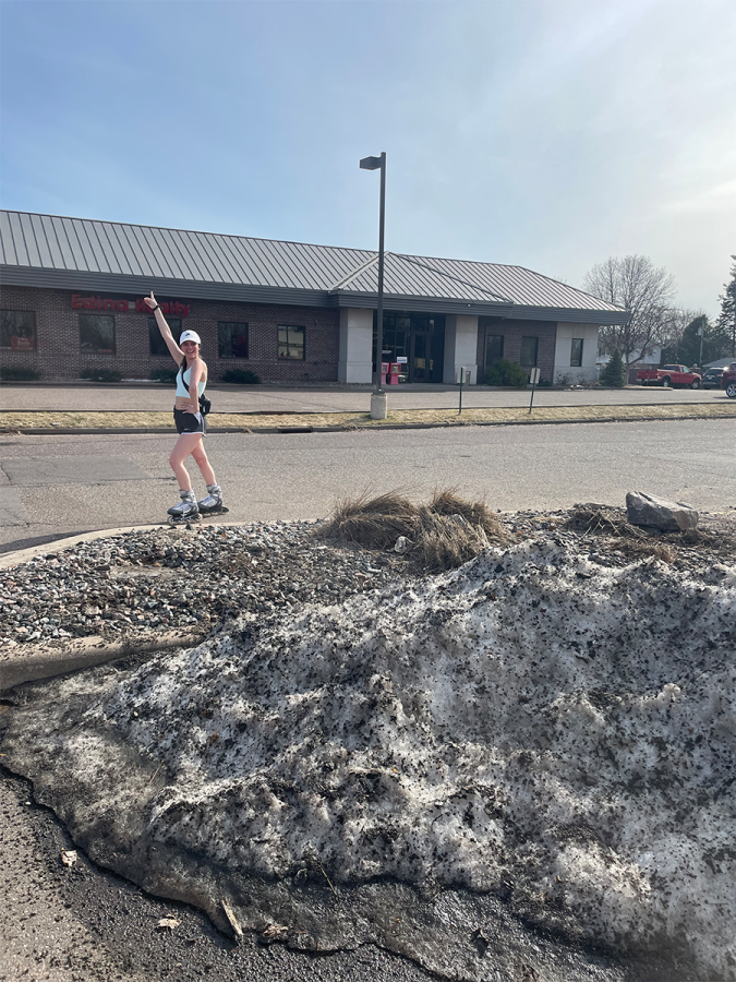 Allison Pazdernick, a second-year nursing student, is seen rollerblading down the road next to a melting pile of snow. Summer activities are in full swing, but winter is still fighting to be relevant.