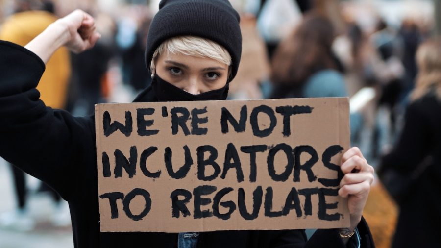 Womens march. Young woman with face mask holding banner sign - We are not incubators to regulate. protest against strict abortion laws. High quality photo