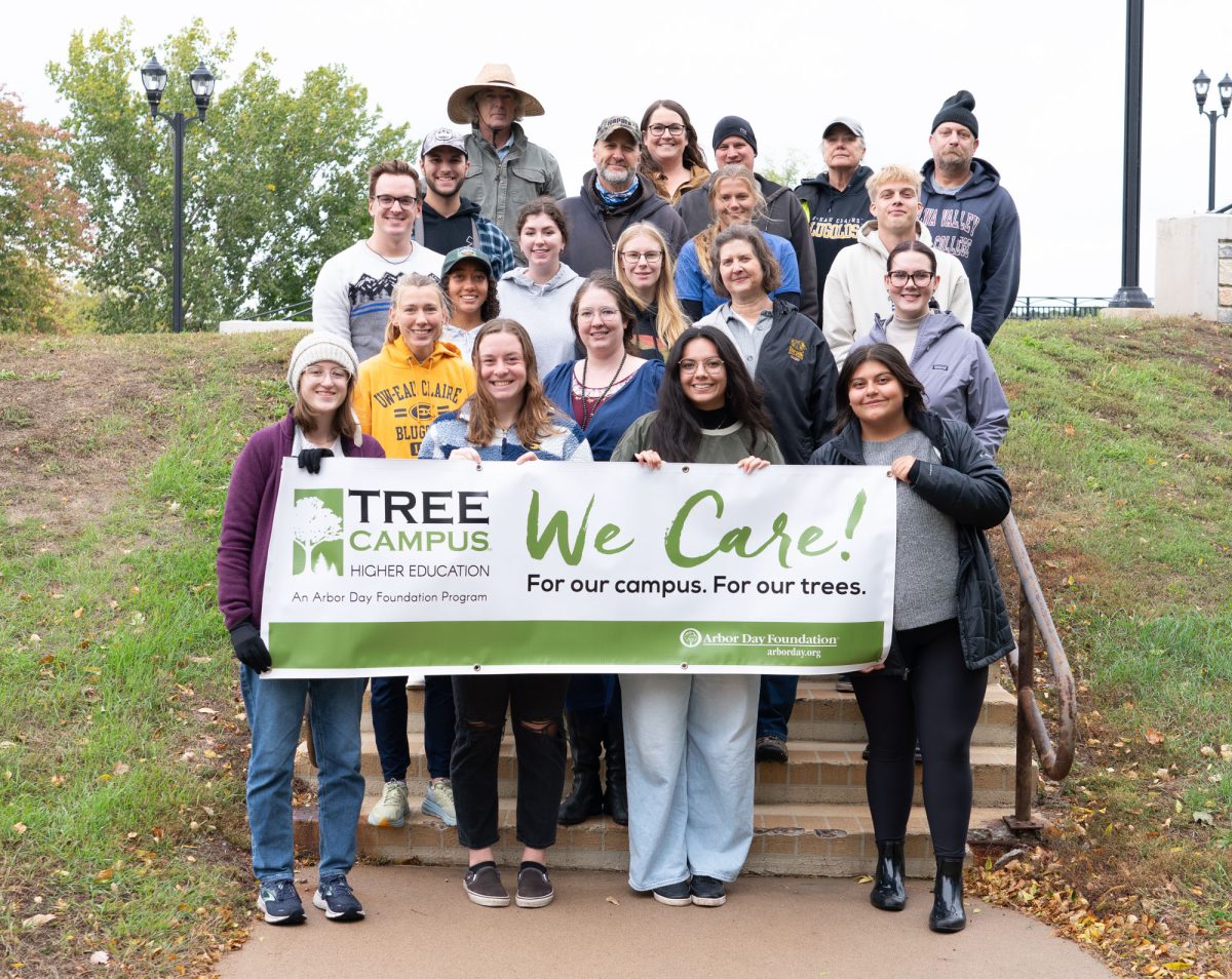 A group of students and faculty pose with a Tree Campus USA banner in celebration of Arbor Day.