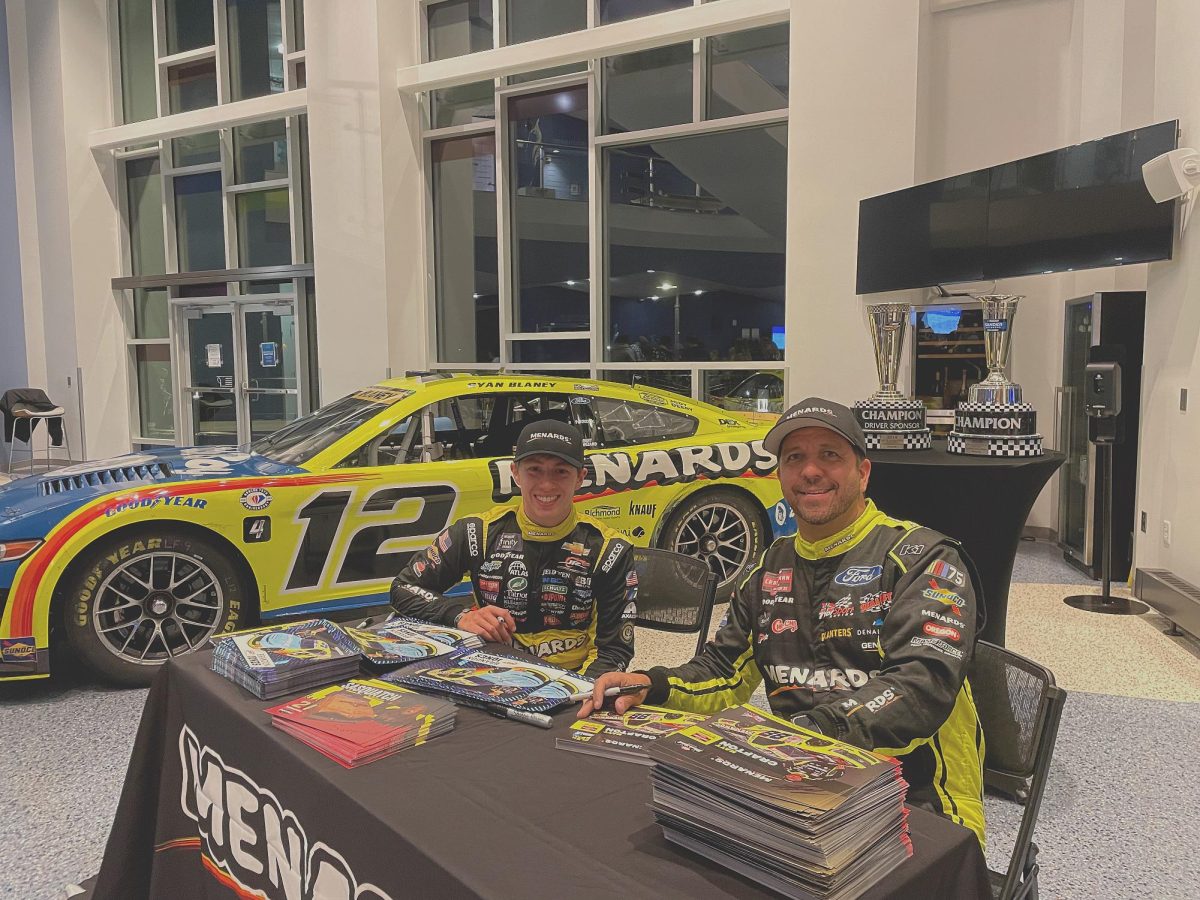 Brandon Jones and Matt Crafton, seated in front of the winning car, hand out their signatures.