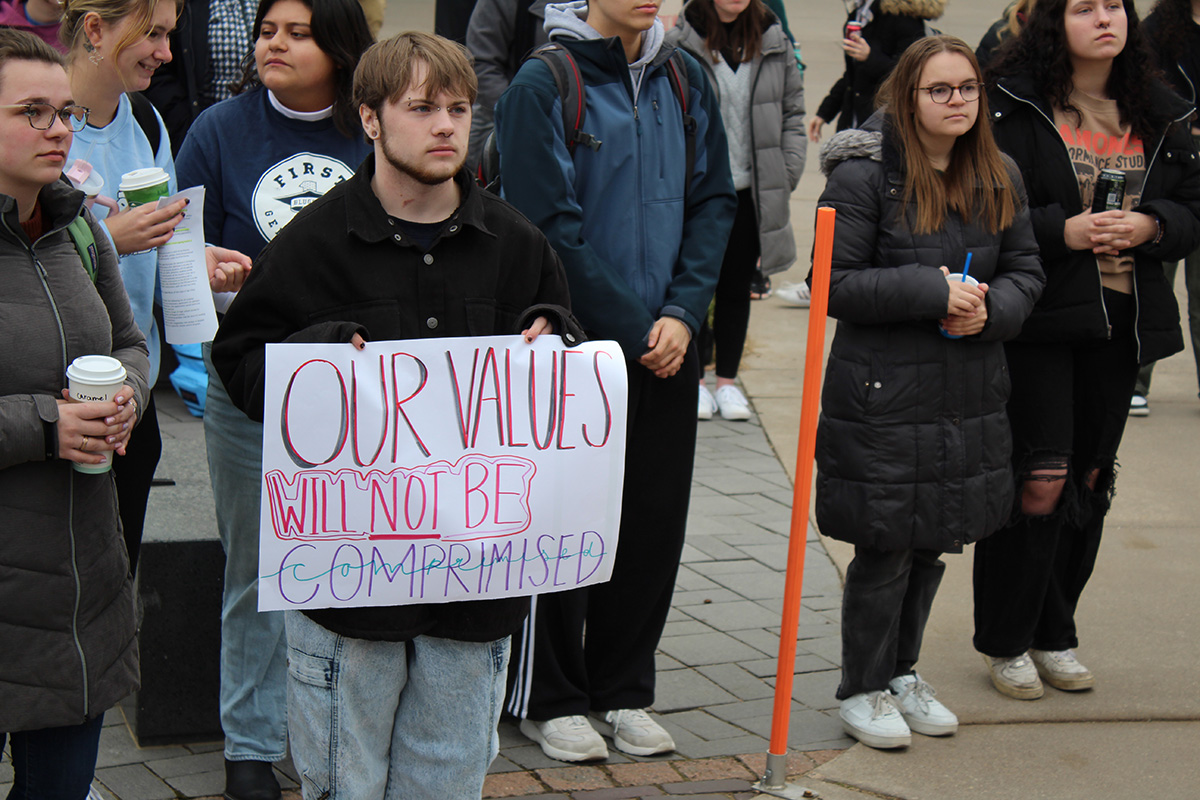 A student holds a sign that says, Our values will not be compromised.
