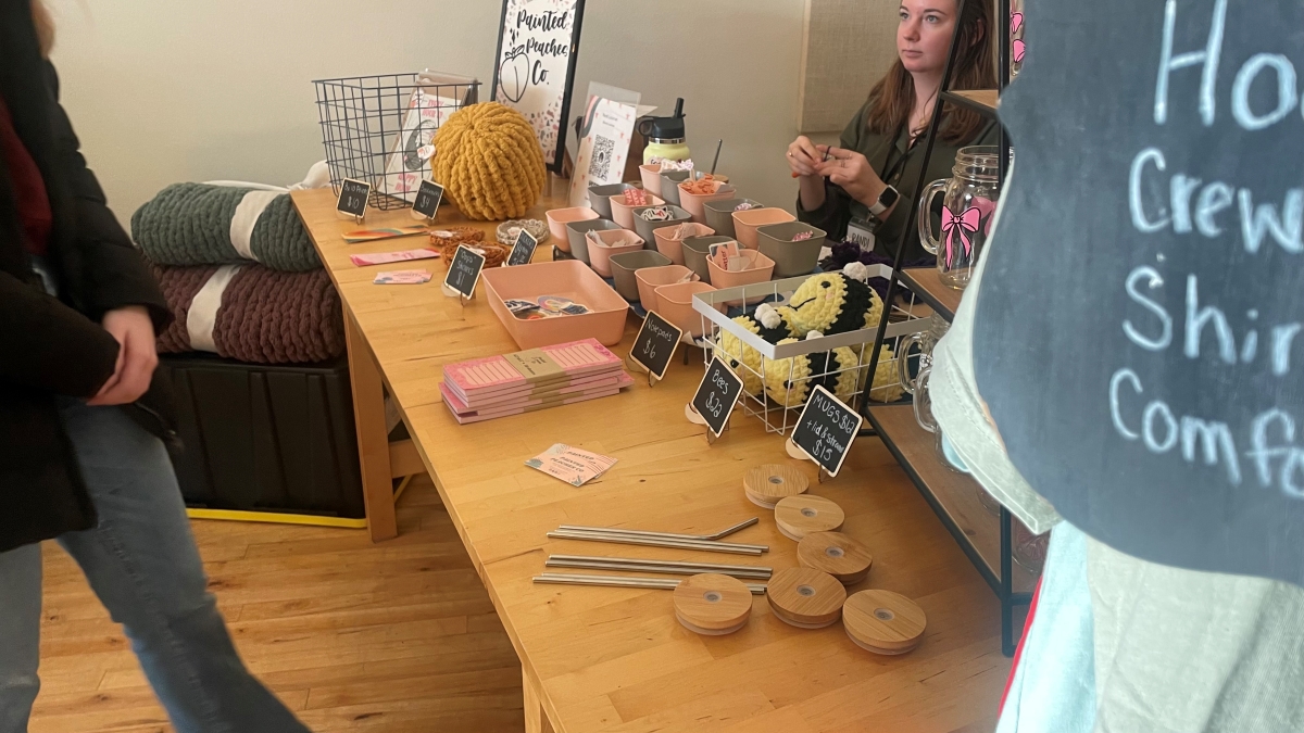 Vendor selling their crocheted bees, stickers and mugs with bamboo lids and metal straws.
